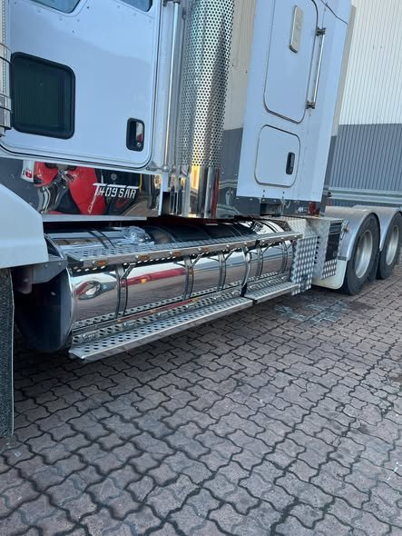 Side view of polished fuel tanks and steps on a Kenworth